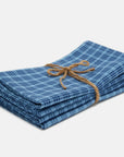 Stack of blue checkered napkins tied with twine on a white background
