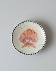 Round ceramic coaster with a shell design on a wooden surface