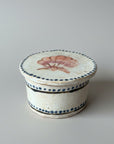 Ceramic container with shell design on a wooden surface