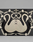 Decorative wall art with cut-out swans and floral elements on a black background