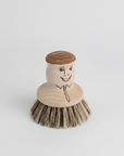 Wooden dish brush with a face design on a white background
